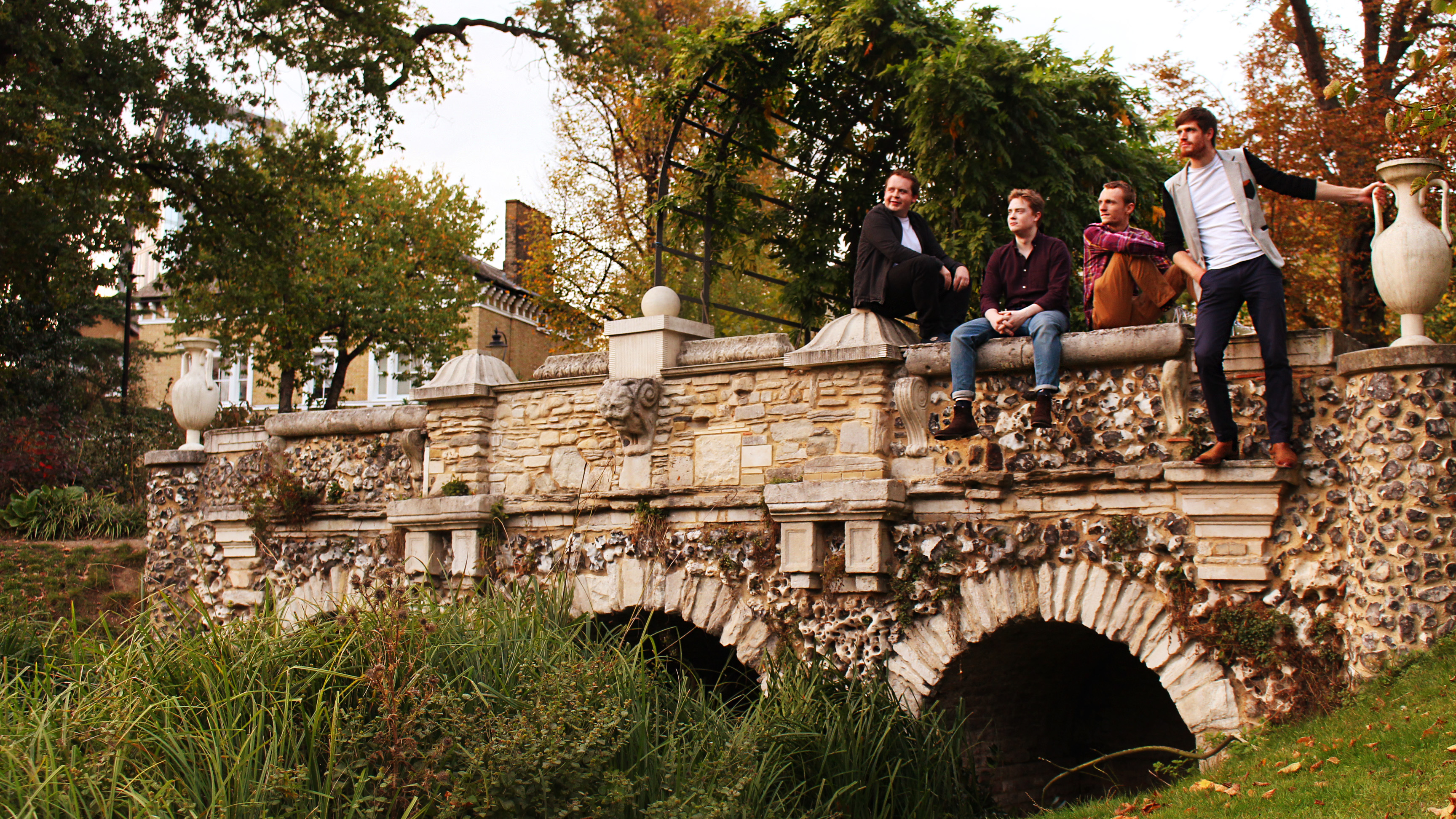 On That Note quartet sitting atop a stone bridge