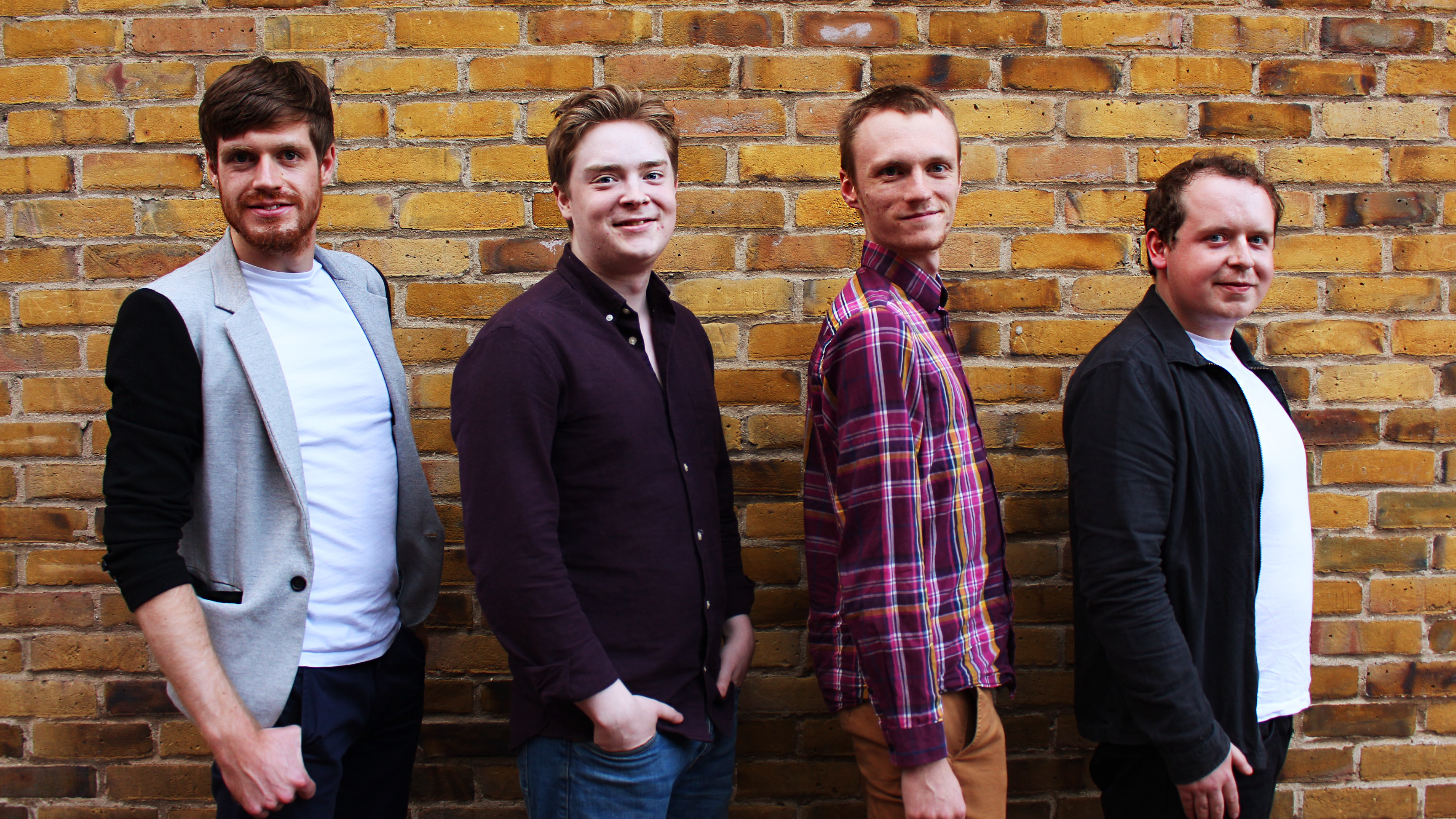 On That Note quartet standing against a brick wall